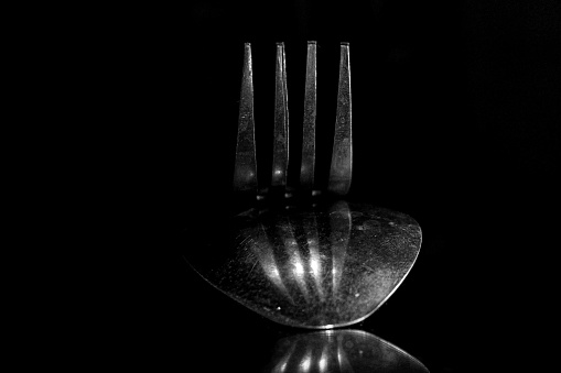 Close up of spoons and forks in a stack, spoons and forks on black background