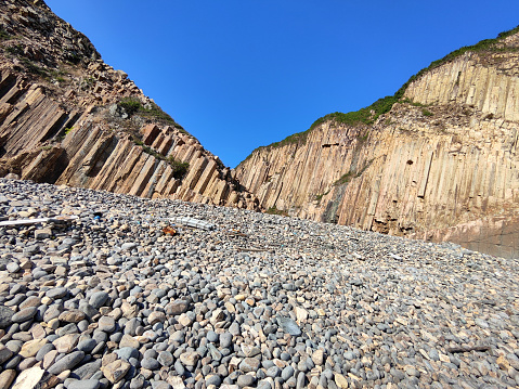 Kim Chu Wan pebble beach, surrounded by Rhyolitic rock columns in the Hong Kong Unesco Global Geopark, Sai Kung peninsula.