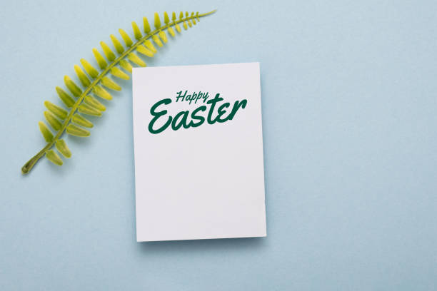 Happy Easter Text on card with green leaf on blue paper background. Postcard easter lettering