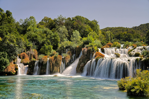 A scenic view of Krka National Park waterfall in Croatia, surrounded by lush foliage