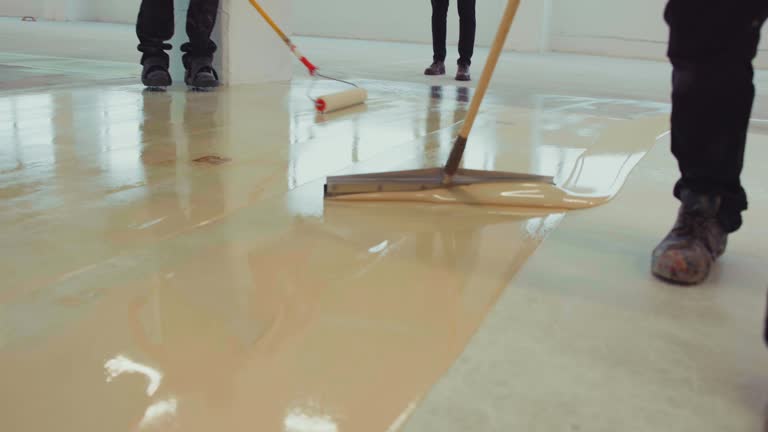 The workers skillfully apply a coat of epoxy resin onto the freshly laid floor, ensuring a seamless and durable finish