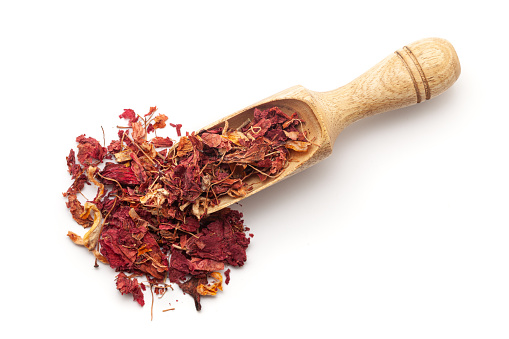 Top view of a wooden scoop filled with Dry Organic Hibiscus (Hibiscus rosa-sinensis) flowers. Isolated on a white background.