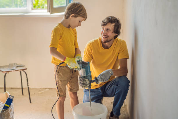 man with his son makes repairs at home, he teaches children to plaster the walls with a spatula in his hands - plaster plasterer work tool child foto e immagini stock