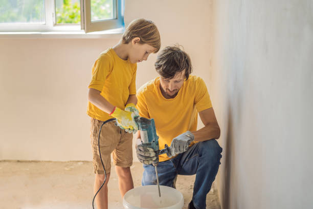 l'uomo con suo figlio fa riparazioni in casa, insegna ai bambini a intonacare le pareti con una spatola tra le mani - plaster plasterer work tool child foto e immagini stock