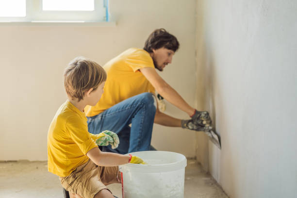 man with his son makes repairs at home, he teaches children to plaster the walls with a spatula in his hands - plaster plasterer work tool child imagens e fotografias de stock