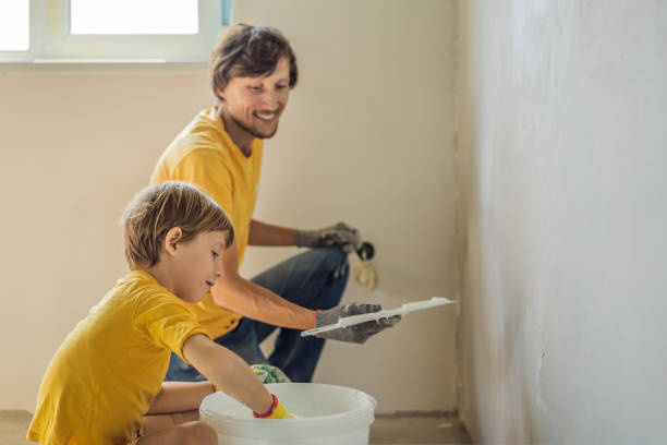 man with his son makes repairs at home, he teaches children to plaster the walls with a spatula in his hands - plaster plasterer work tool child imagens e fotografias de stock