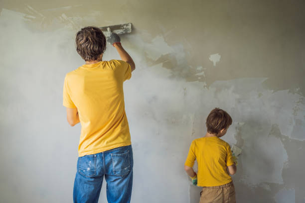 man with his son makes repairs at home, he teaches children to plaster the walls with a spatula in his hands - plaster plasterer work tool child imagens e fotografias de stock