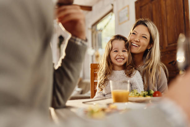 Happy mother and daughter talking to a father at dining table.