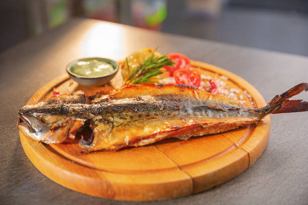 Grilled fish with fresh garnishes on a wooden board