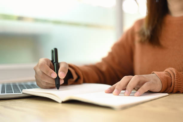 istock Cropped shot young woman writing down ideas or planning next weekend on notebook 2042245961