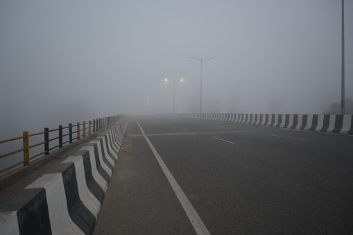 Lonely woman walks on empty road in mist. Journey to unknown place. Solitude female person walking outdoors