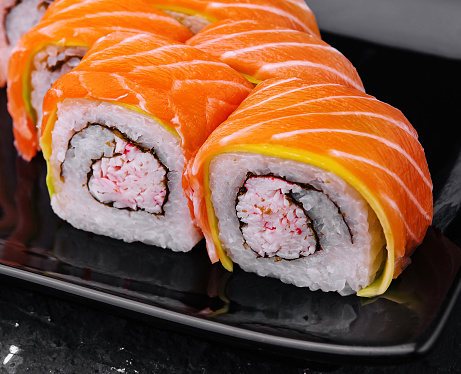 sushi rolls with salmon and crab on black plate