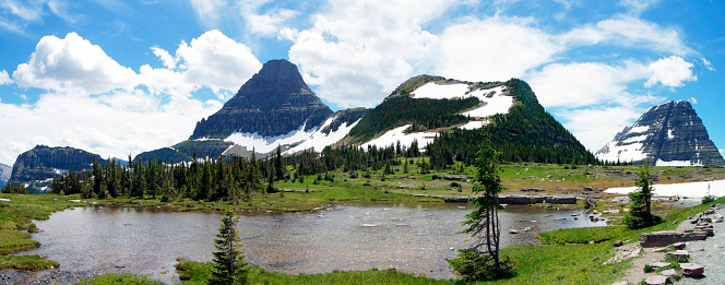 Teal green alpine lake, surrounded by mountains and stormy weather