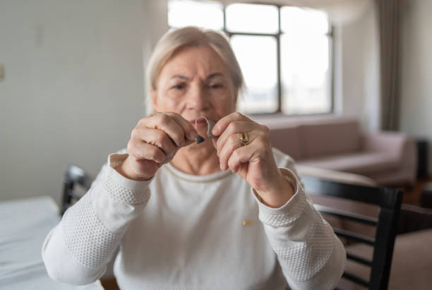 istock Old Woman Holding A Hearing Aid 2042353812
