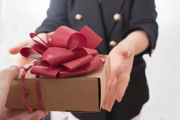 istock Mature woman recieving a present with red ribbon 2042363098