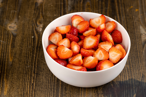 Close-up of bowl of fresh strawberries. Freshly harvested strawberries in a ceramic bowl over wooden table.