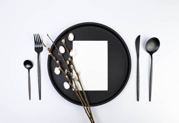 istock Top view of black plate and cutlery, white card, pussy willow branches, white easter eggs on white background. 2042388973