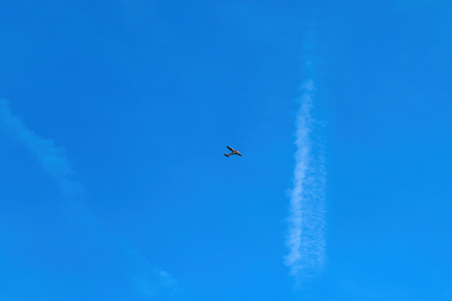 Small airplane or light aircraft flying across the blue sky, low angle view