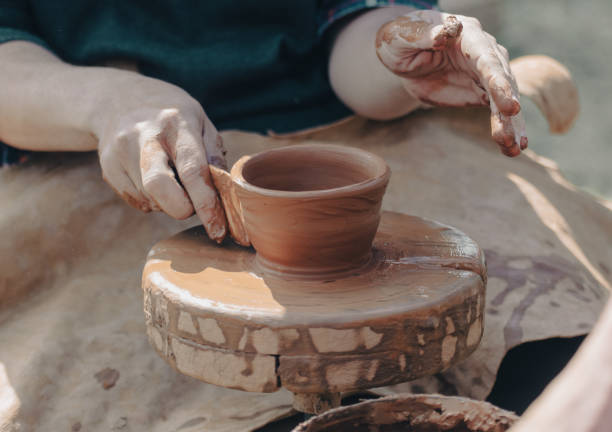 istock hands of a potter, creating an earthen jar on a pottery wheel 2042408528