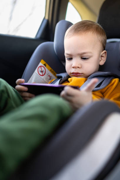 istock Little boy using smart phone while sitting in car back seat. 2042422930