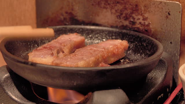 View of frying pork chops coated with breadcrumbs in a cast iron frying pan