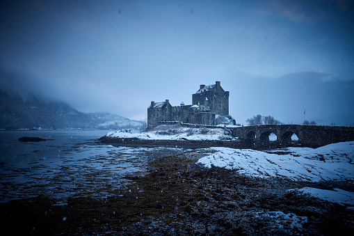 Eilean Dornie Castle on Loch Duich during winter, everything is covered with snow. It is in December 2022 when a heavy layer of snow falls in the west of Scotland. It’s still snowing