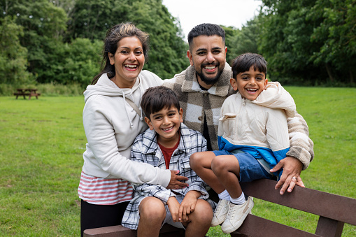 A mid adult couple and their sons enjoying a day outdoors in a public park in Ponteland, North East England. They are all looking at the camera and smiling.