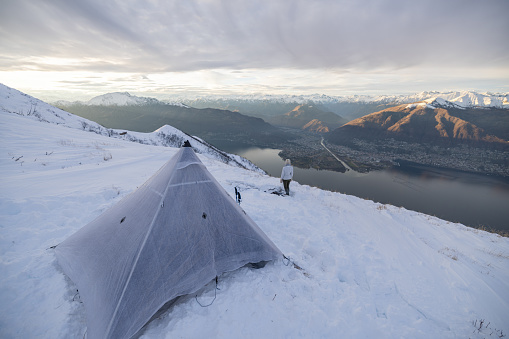 Backcountry skier sets up camp on snow slope in the evening