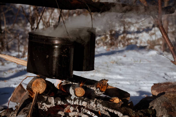 istock Two pots simmering over a wood fire in snowy landscape 2042515069