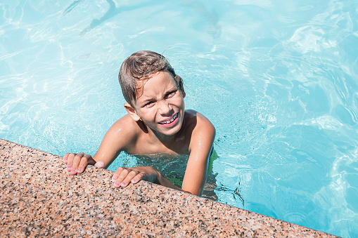 Children in bathing suits play in pool in the summer.