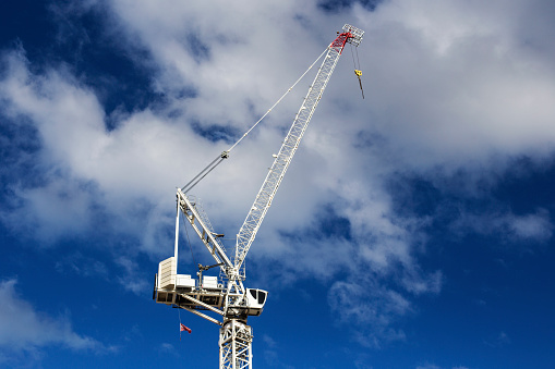 Single crane used in construction against a blue cloudy skyline.