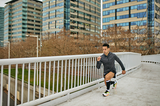 Full length view of mature male athlete in sports clothing doing walking lunges.