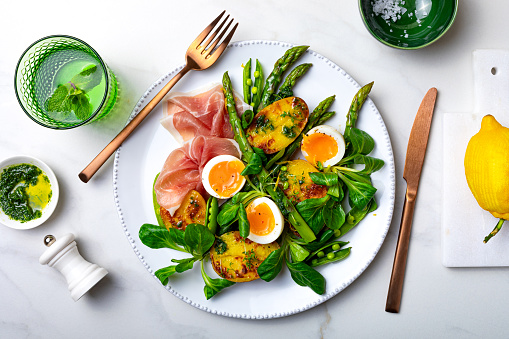 Grilled green asparagus, roasted new baby potatoes, fresh corn salad leaves, soft boiled egg, prosciutto, peas and green herb oil salad.