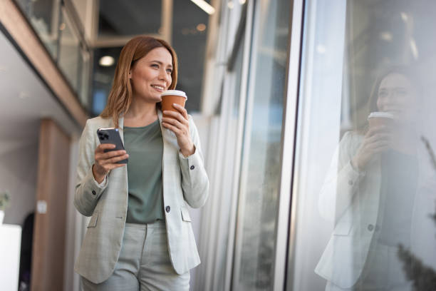 istock Smiling businesswoman using phone in office 2042565488