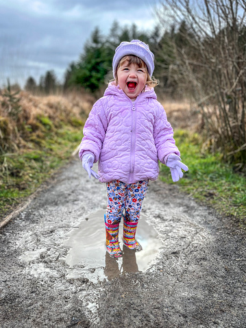 Two year female toddler lifestyle shoot splashing in puddles in wellington boots
