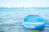 Lonely sup board on the sea on floating sailboats background