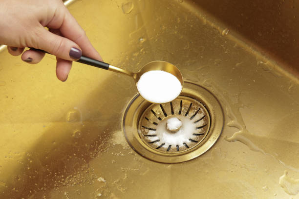 istock Cleaning kitchen sink with bakIng soda to keep sinks draining well and prevent clogs. Safe, effective, cheap, natural solution for clogged drains. 2042587719