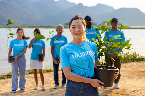 Team of young Asian diversity volunteer worker group enjoy charitable social work outdoor in tree forest planting NGO work for climate change and global warming coastline habitat project