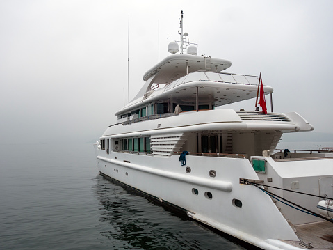 A luxury yacht docked at the marina in foggy weather.