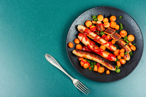 Grilled German turkey meat sausages in tomato sauce with roasted carrots on the plate. Space for text.
