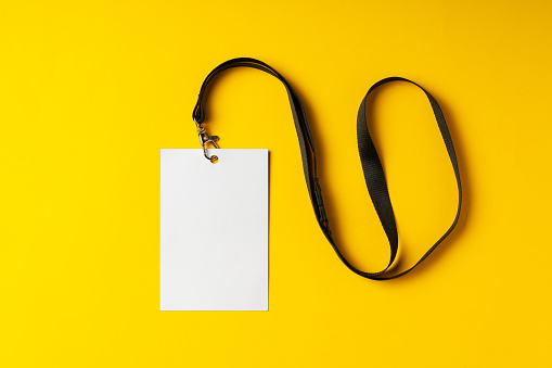 Blank nametag on a string on yellow background copy space close up