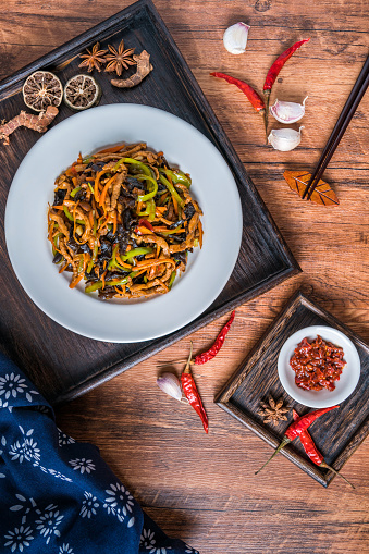 A plate of Sichuan cuisine and fish flavored shredded pork on a wooden table