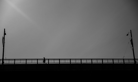 silhouette of woman walking on a bridge