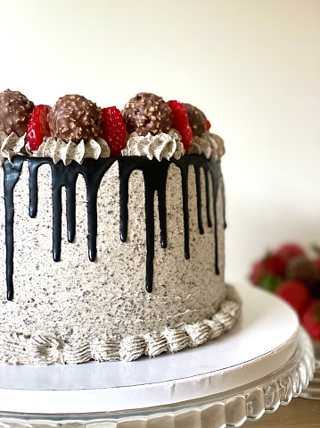 cake with topping strawberry and ferrero rocher and chocolate dripp.