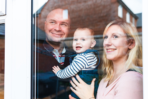Happy family portrait, smiling and looking through the window - Happy little boy with mother and father enjoying time together and having fun - Lifestyle and family concepts