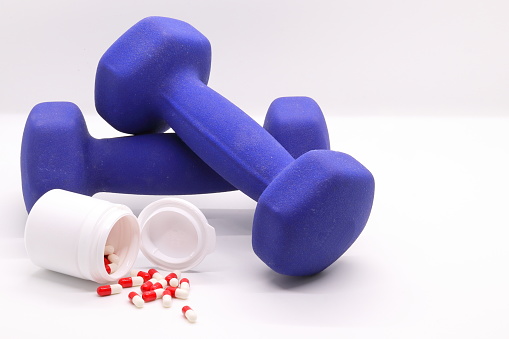 Close-up of dumbbells for sports and capsules with synthetic food supplements