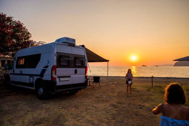 Campervan is parked on the beach at sunset. Campervan is parked on the beach next to the sea - wild camping in Croatia, Montenegro, Albania or Greece. Summer road trip.