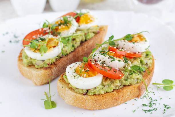istock Delicious toast with avocado, boiled egg, tomatoes and microgreen on a white plate. Healthy eating, breakfast. Keto diet food. Trendy food. 2042718977