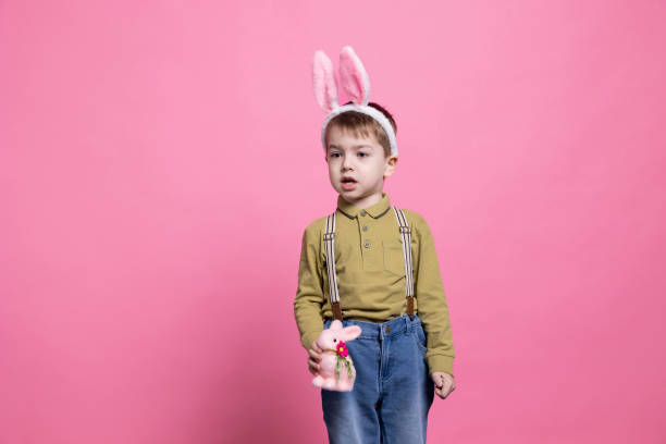 istock Small cute boy wearing bunny ears and holding a stuffed rabbit in studio 2042721021