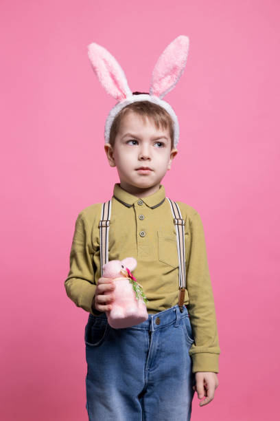 istock Young happy toddler showing a decorated fluffy rabbit in studio 2042721103